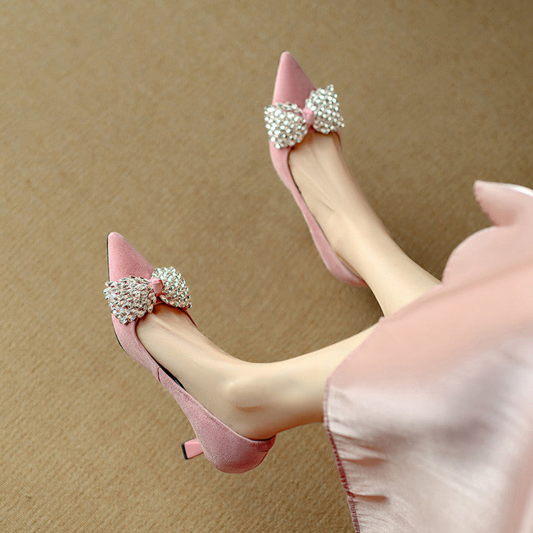 Pink high-heeled shoes with decorative bows worn by a person on a beige background