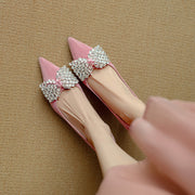 Pink high-heeled shoes with silver bow decorations on a beige background