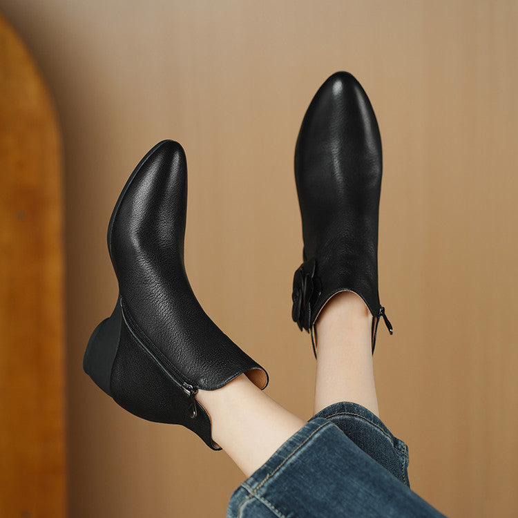 Black ankle boots worn with jeans against a brown background