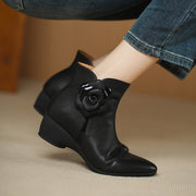 Black ankle boots with floral design on a beige surface