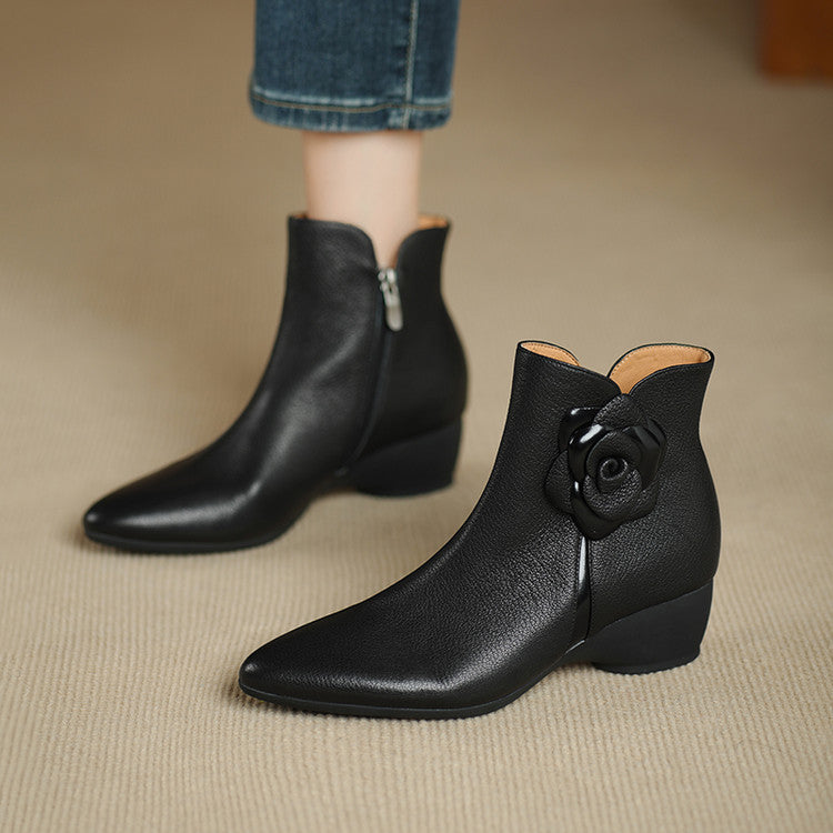 Black ankle boots with a floral detail on a beige surface