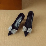 Black high-heeled shoes with decorative crystal embellishments on a beige background