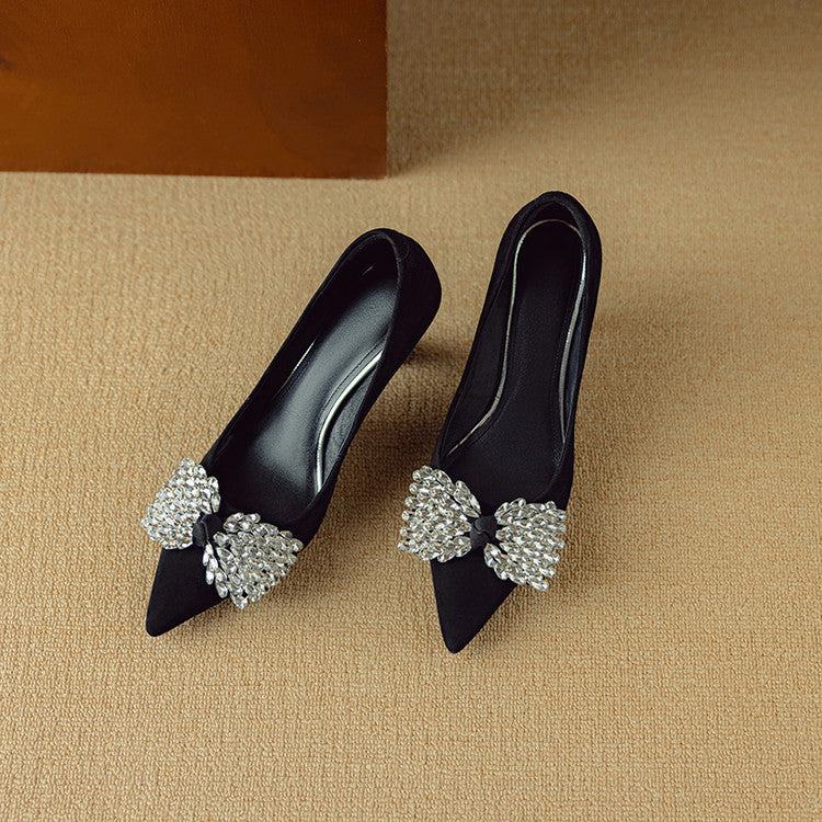 Black high-heeled shoes with decorative crystal embellishments on a beige background