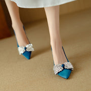 Blue high-heeled shoes with decorative bows on a beige surface