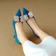 Blue high-heeled shoes with decorative bows on a beige background