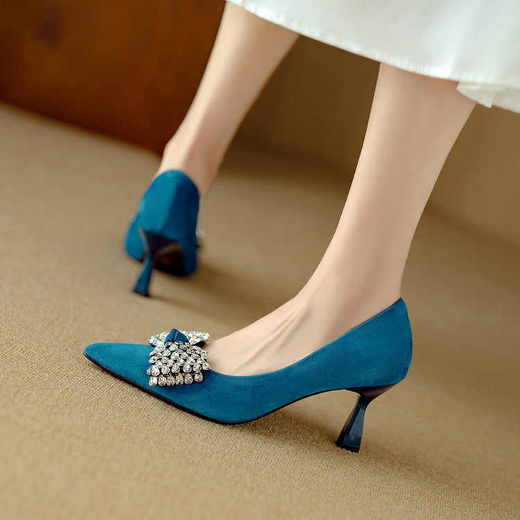 Blue high-heeled shoes with a decorative brooch on a beige surface