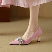 Pink high-heeled shoes with a decorative bow on a beige background