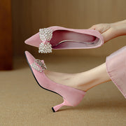 Pink high-heeled shoes with decorative bows on a beige background