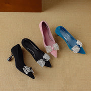 Four high-heeled shoes with decorative bows on a beige surface