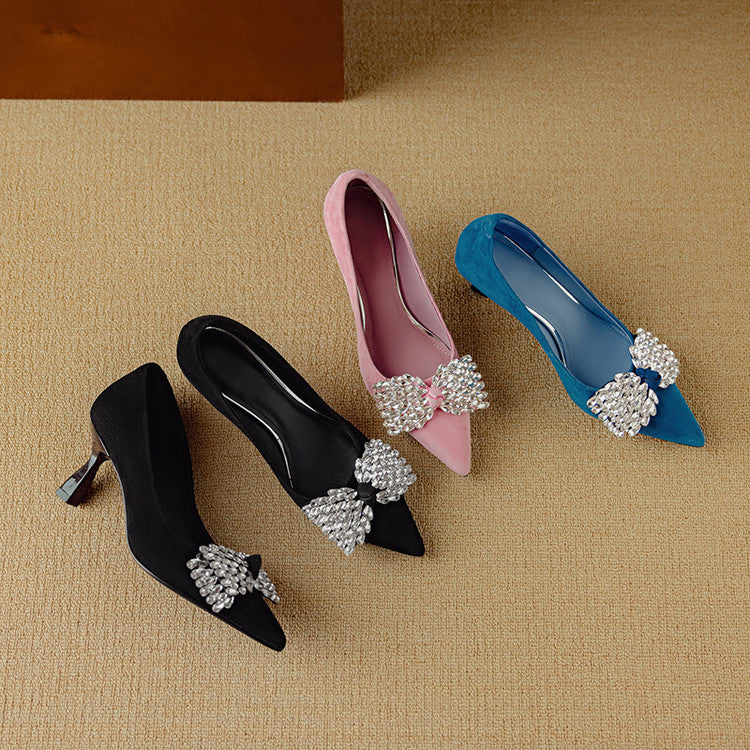 Four high-heeled shoes with decorative bows on a beige surface