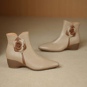 Pair of beige ankle boots with floral decorations on a beige background